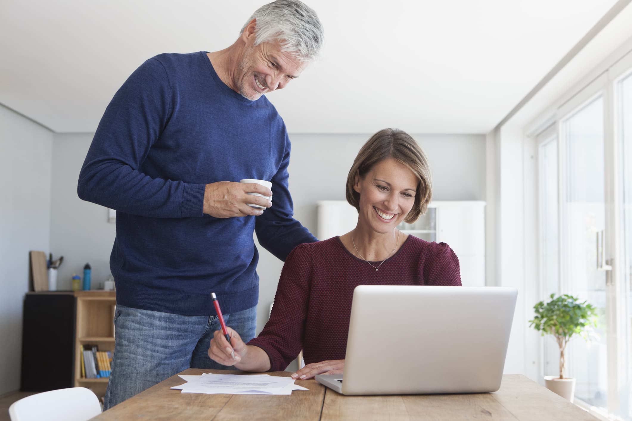 Older male and female couple using laptop on table.